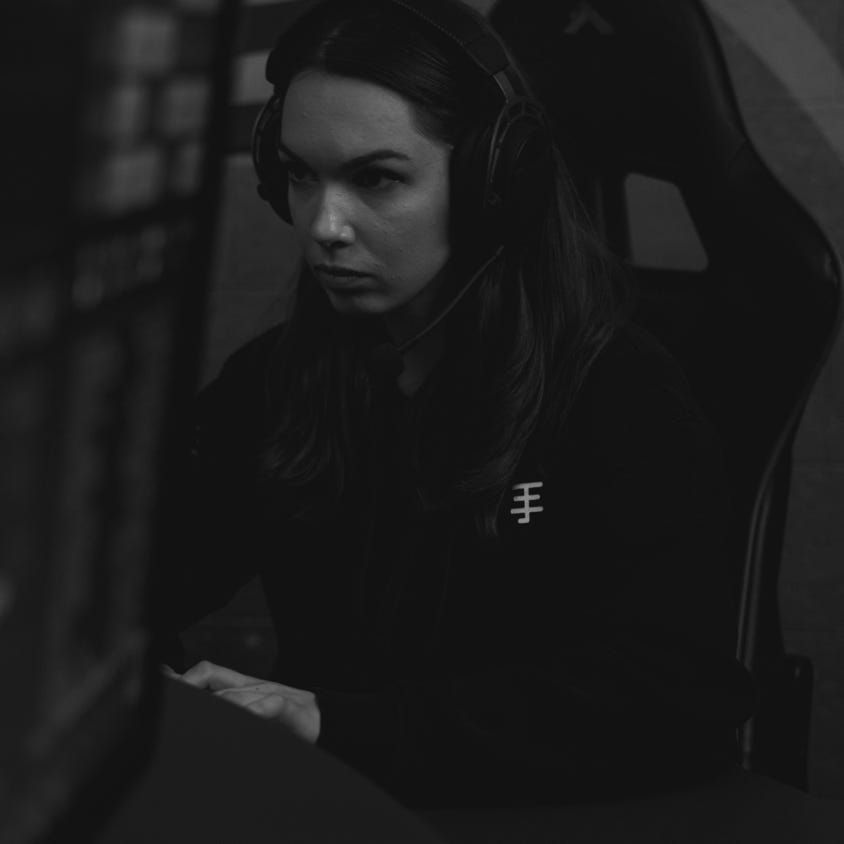 A focused female gamer wearing a headset, immersed in a gaming session indoors.